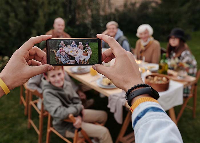 Unrecognizable person taking photo of family dinner on smartphone.